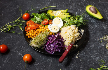 Wall Mural - Healthy vegan lunch bowl. Vegan buddha bowl. Vegetables and nuts in buddha bowl on black concrete background