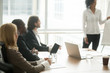 © fizkes - Diverse business people executive team listening to presentation, multiracial businesspeople sitting at conference meeting table at briefing, attending corporate group training or business seminar
