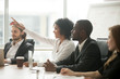 © fizkes - African woman raising hand to ask question at team training, curious black employee or conference seminar participant vote as volunteer at group office meeting with multiracial diverse businesspeople
