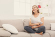 © Prostock-studio - Young smiling woman sitting on beige couch