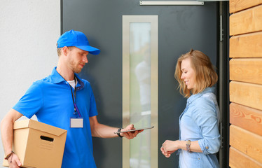 Smiling delivery man in blue uniform delivering parcel box to recipient - courier service concept. Smiling delivery man in blue uniform