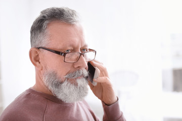 Canvas Print - Senior man talking on mobile phone at workplace in office