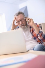 Canvas Print - Senior man talking on mobile phone while working in office