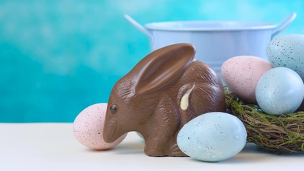 Wall Mural - Australian milk chocolate Bilby Easter egg with eggs in nest against a blue and white background.