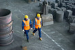 © Seventyfour - High angle view of two bearded technicians wearing uniform and hardhats walking along production department of modern plant