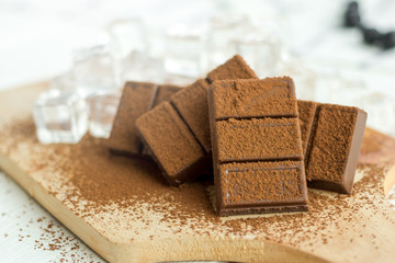 Wall Mural - Close up a chocolate bar and ice cubes on wooden plate