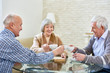 © Seventyfour - Portrait of three happy senior friends enjoying tea time meeting at home and sharing memories, focus on nice elderly lady holding tea cup