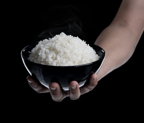 Sticker - Hand holding a bowl with cooked rice on black background