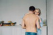 © LIGHTFIELD STUDIOS - girlfriend hugging shirtless boyfriend and looking at camera at kitchen