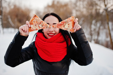 Funny brunette girl outdoor on winter with two pieces of pizza.