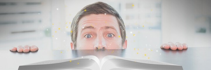 Wall Mural - Man looking at an opened book with lights on a table