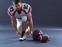 American Football Player Tie His Shoe Laces Isolated On Gray
