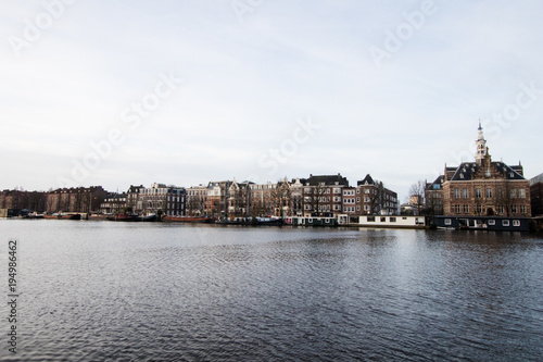 Zdjęcie XXL Wielokolorowe domy w Amsterdamie na głównym kanale miasta. Typowy holenderski holenderski dom z wieloma oknami i pionowo rozwinięty. Łodzie na dole