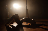 Young sexy woman exercise pole dance on a dark background