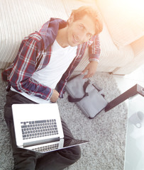 Canvas Print - business guy with laptop sitting on carpet in living room.