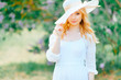 © benevolente - Young cute pretty blonde amazing model girl in white dress portrait in park outdoor. Beautiful happy girl with expressive face in blooming lilac garden. Spring is coming. Branches and trees. Easiness.