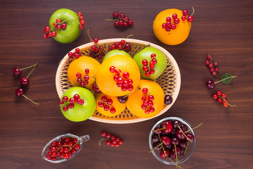 Wall Mural - Fruits and berries. Apple, orange, cherry and currant on wooden table.