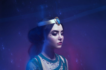 Wall Mural - A girl in oriental attire, Queen of the storm. Princess Jasmine. The background is a twist and a strong wind. Studio shooting with mixed light. Artistic Photography