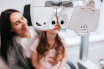 Wall Mural - Mom with daughter in ophthalmology clinic