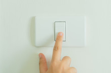 Close Up Of Finger Turning Off On Light Switch On Wall.