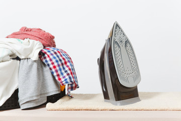 Wall Mural - Close up steam iron, ironing colorful clothes, washed laundry, family clothing on ironing board isolated on white background. Housekeeping concept. Copy space for advertisement. With place for text.