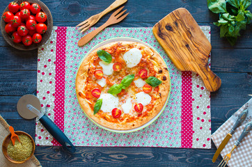 Top view of italian classic pizza margherita over a wooden table with toppings