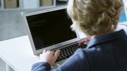 Tracking shot of primary school children studying with their laptops in coding computer class