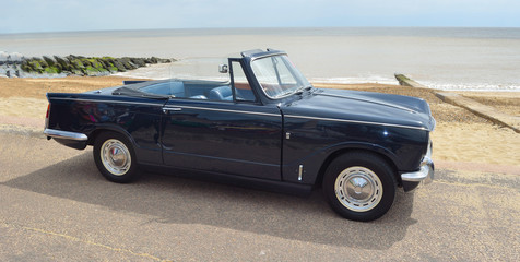 Wall Mural - Classic Black Triumph Vitesse open top parked on seafront promenade.