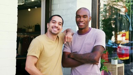 Wall Mural - Two young men smiling to camera outside their clothes shop