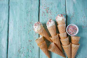 Wall Mural - vanilla ice cream in waffle cones over turquoise wooden surface