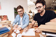 © Vadym Huzhva - Two freelancer men taking notes at laptop at desk surrounded by books.