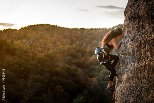 Fotografie, Obraz Female climber on a wall climbing at sunset