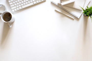 White office desk table with laptop, cup of coffee and supplies. Top view with copy space, flat lay.