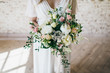 Gorgeous bouquet of white and pink flowers in the hands of the charming bride in a white dress. Artwork