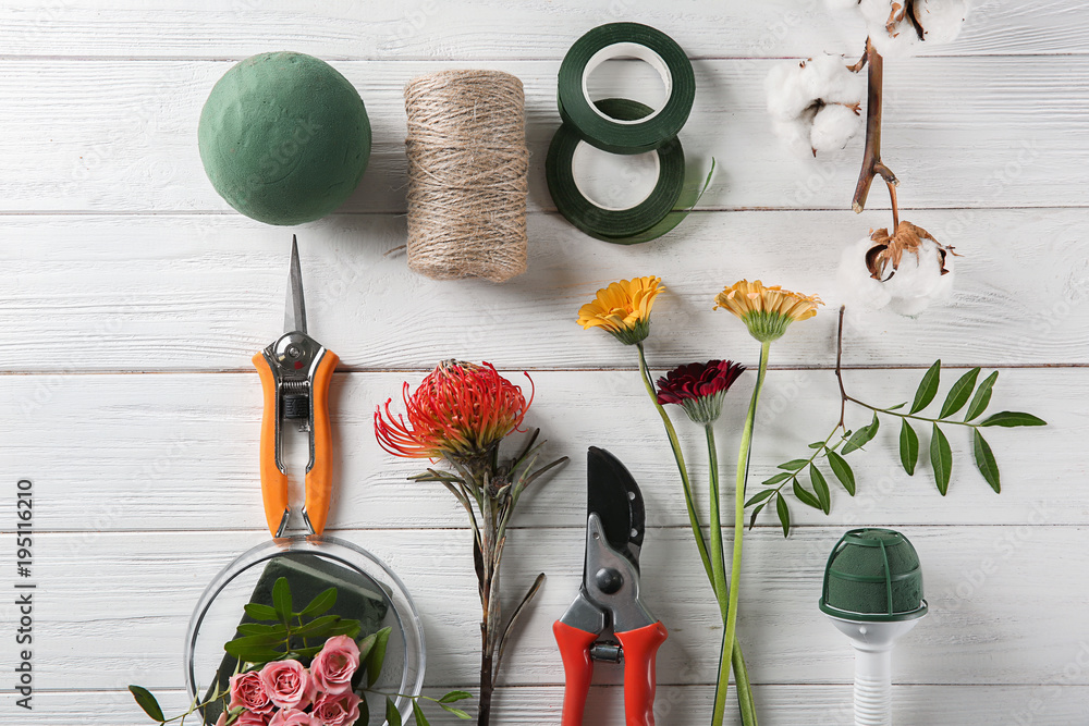 Florist equipment with flowers on wooden background