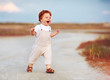 © Olesia Bilkei - adorable redhead toddler baby boy in jumpsuit running through the summer road and field