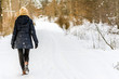 © alicja neumiler - Woman walking in snow in winter clothes. Girl on snowy road in park.