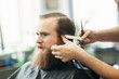 © Aleksandr - Barber using scissors and comb in barbershop