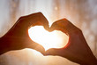 © SecondSide - Female hands in the form of heart against window of sunlight. Hands in shape of love heart, silhouetted against the sun