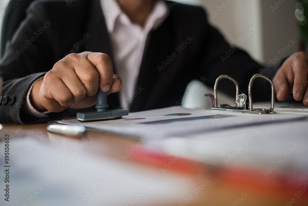 Businessman hand pressing rubber stamp approved on business contract document