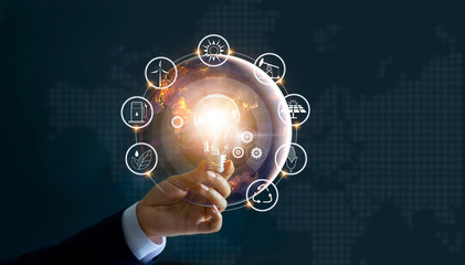 Wall Mural - hand holding light bulb in front of global show the world's consumption with icons energy sources fo
