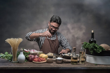 Wall Mural - Handsome bearded cheef cook prepairing spaghetti on a kitchen.