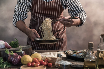 Wall Mural - Handsome bearded cheef cook prepairing spaghetti on a kitchen.