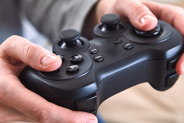 Poster - man holding a joystick controllers while playing a video games at home