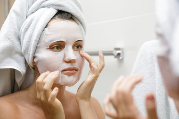 Sticker - Woman in bathroom is applying facial sheet mask