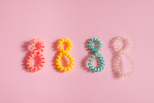 Colorful Hair Bands In The Form Of Number 8 On Pink Background. Place For Text, Design, Pattern.