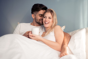 Canvas Print - Picture of young couple drinking coffee in bed.