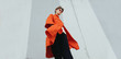© Audrey Shtecinjo/Stocksy - Alternative stylish young female on orange/red coat on street/minimalist composition.