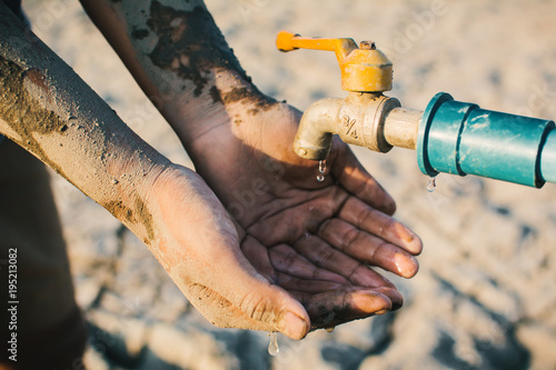 Hand of boy want to drink some water on crack ground , Concept drought and shortage of water crisis