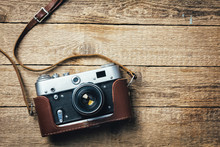 Old Vintage Film Photo Camera With Brown Leather Strap On Grunge Wooden Table. Photographe Concept Background